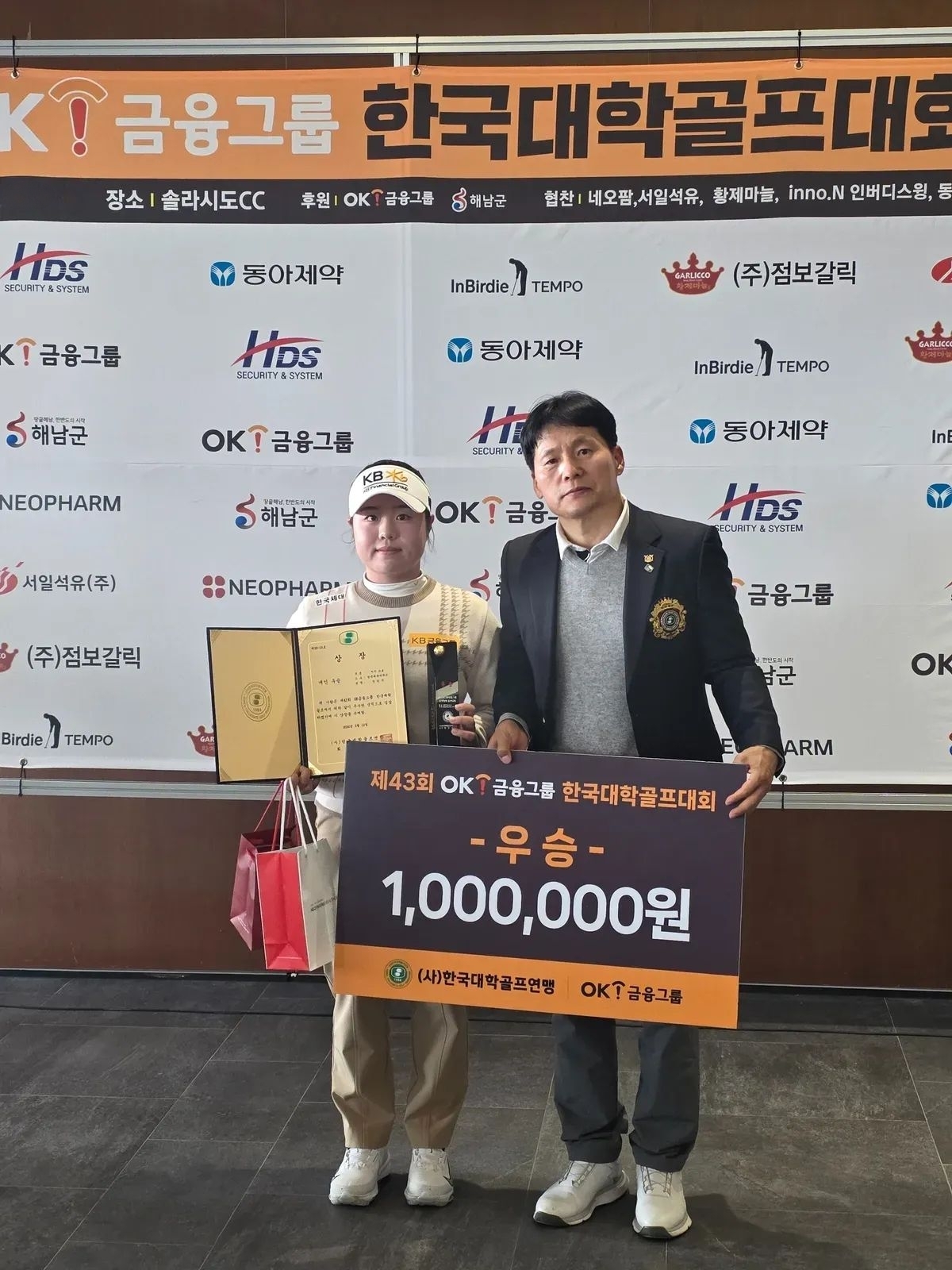 OK금융그룹은 한국대학골프연맹과 함께 ‘제43회 OK금융그룹 한국대학골프대회’를 개최했다. 프로 대학부(여자 개인전 부문)에서 최종 우승한 9기 OK골프장학생 출신 정민서 선수(왼쪽)와 한국대학골프연맹 박영민 수석부회장이 기념촬영을 하고 있다. OK금융그룹 제공