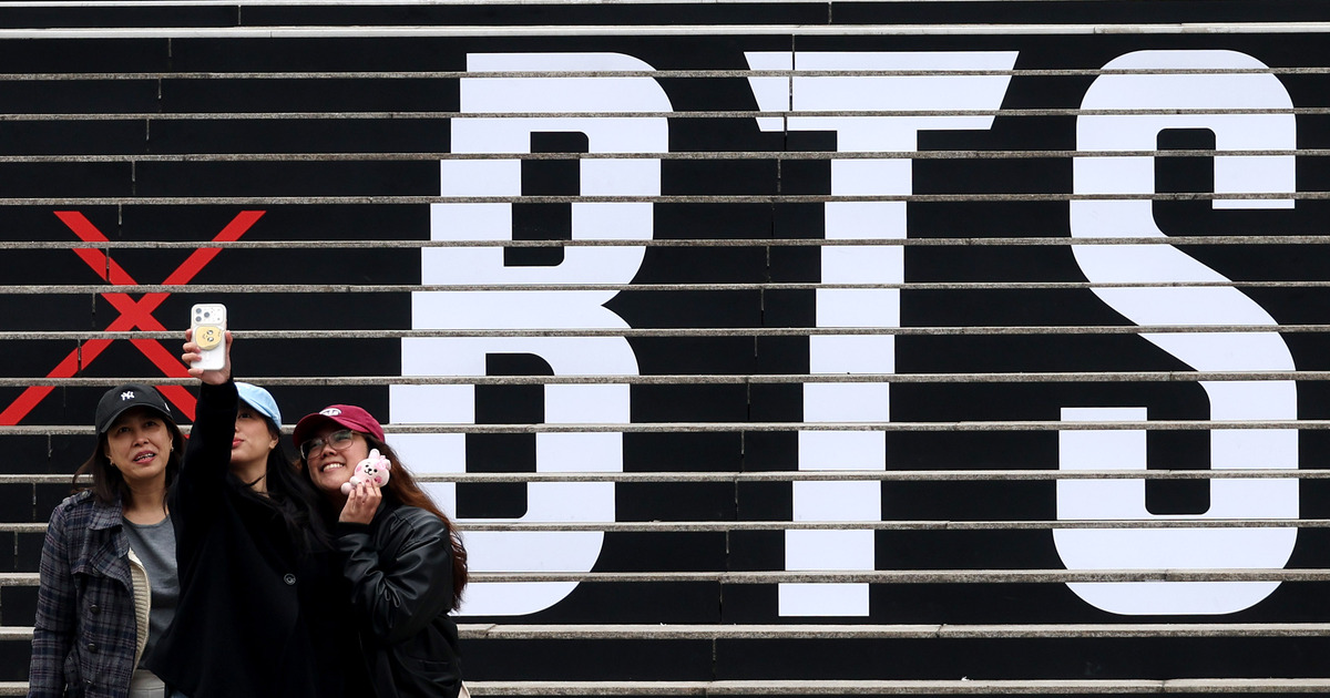 방탄소년단(BTS)의 서울 광화문광장 컴백 공연을 엿새 앞둔 15일 오후 서울 종로구 세종문화회관 계단에서 외국인관광객이 BTS 컴백 공연 관련 래핑 광고를 배경으로 기념촬영을 하고 있다. 뉴시스