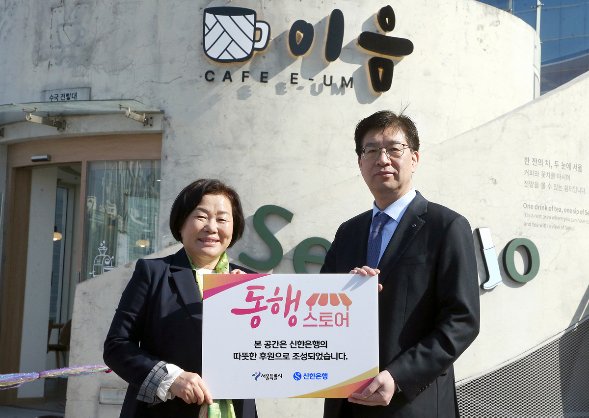 25일 서울로7017에서 진행한 ‘동행스토어’ 3호점 ‘카페 이음’ 개점식에서 강영홍 신한은행 경영지원그룹장(오른쪽)과 서정화 열린여성센터 원장이 기념촬영하는 모습. 신한은행 제공