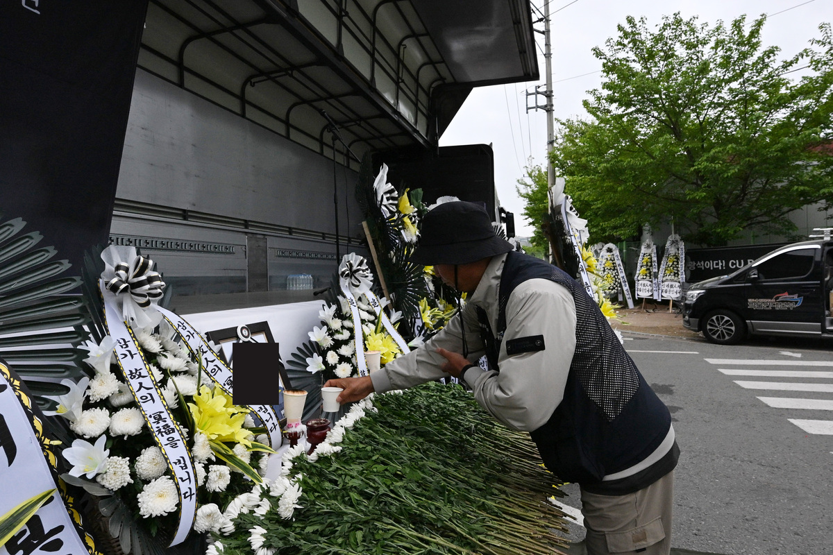 22일 경남 진주시 BGF로지스 진주센터 인근에 지난 20일 사고로 숨진 화물연대 조합원 A씨를 추모하는 합동분향소가 차려진 가운데 한 동료가 영전에 커피한잔을 올리고 있다. 뉴시스
