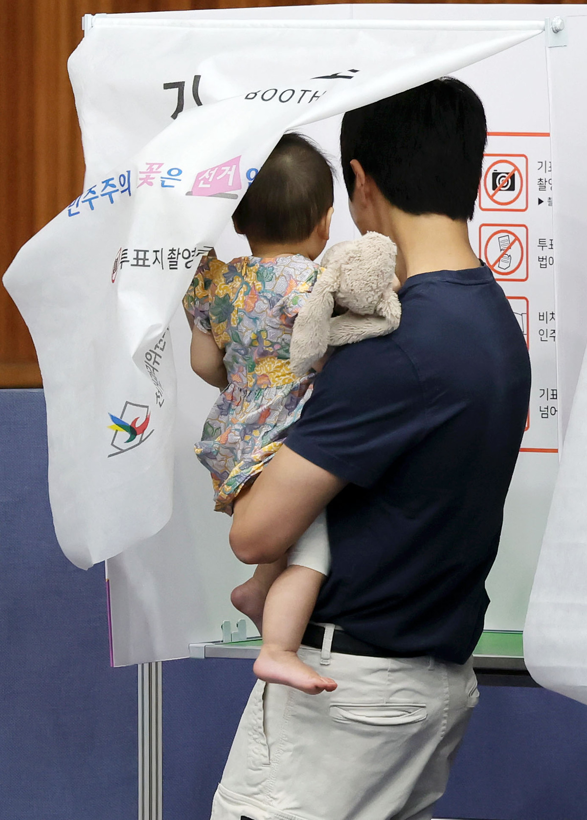 3일 서울 송파구 잠전초 체육관에 마련된 잠실본동 제4·5·6투표소에서 아기가 아빠 품에 안겨 기표소로 들어가고 있다. 뉴시스