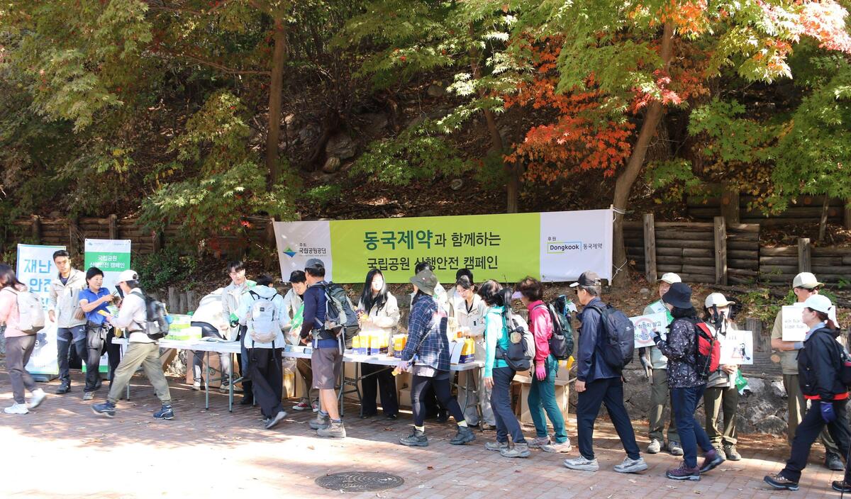 동국제약과 국립공원공단 임직원이 산행 안전수칙과 구급함 위치가 표시된 지도를 도봉산 탐방객에게 배포하고 있다.