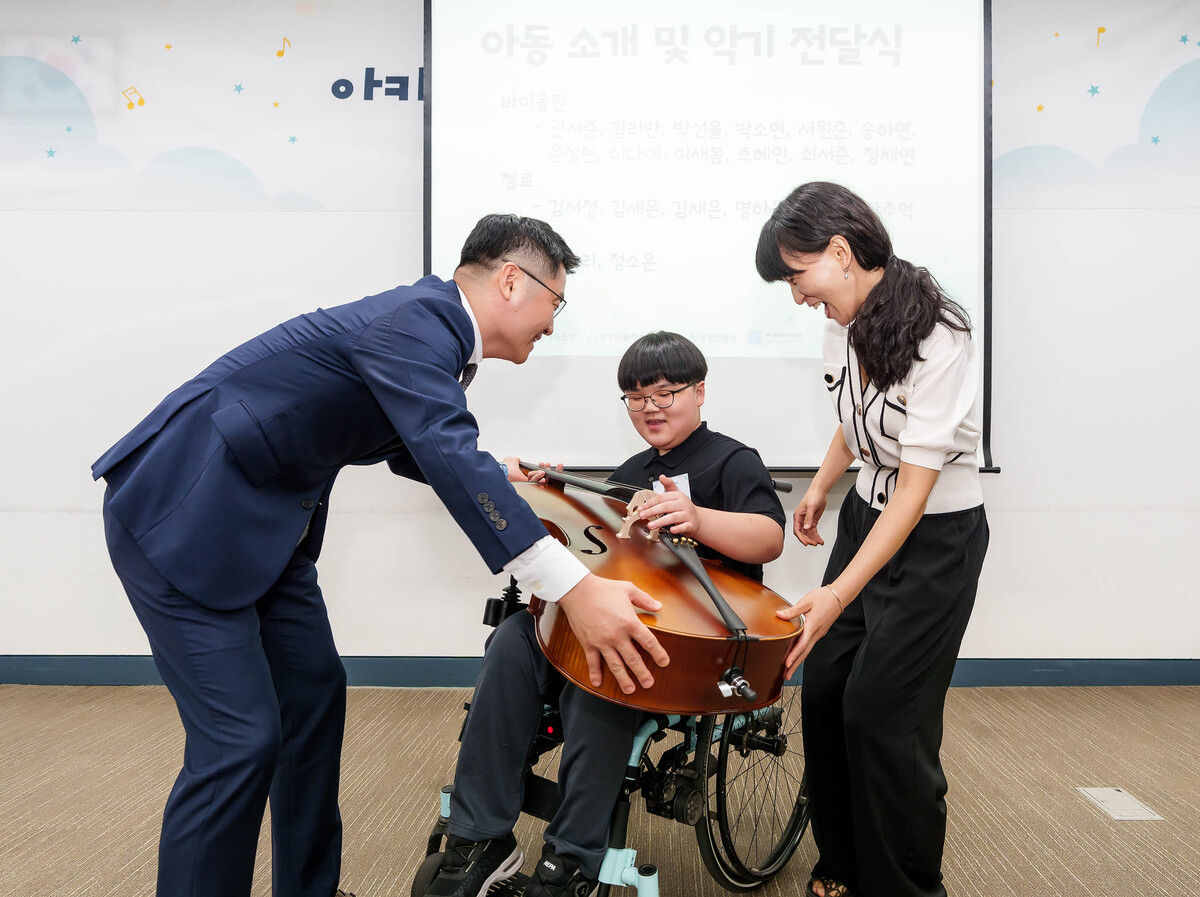 유준원 상상인그룹 대표가 휠체어 사용 아동에게 오케스트라 악기를 수여하고 있다.&nbsp;상상인그룹은 단순한 휠체어 지원을 넘어&nbsp;2023년부터&nbsp;‘아카데미 상상인’&nbsp;음악교육을 진행해오고 있다.상상인그룹&nbsp;제공
