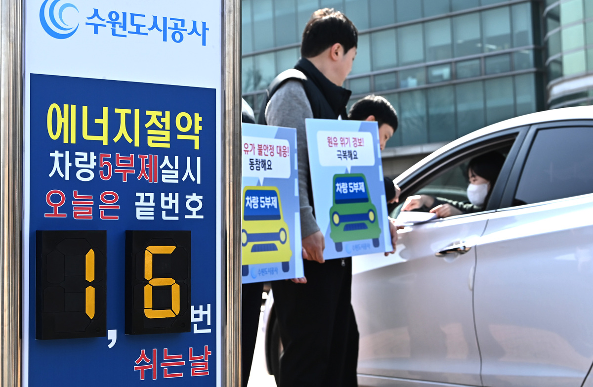 수원도시공사 직원들이 지난 23일 경기 수원시 더함파크 주차장 입구에서 운전자에게 차량 5부제 시행 안내문을 전달하고 있다. 뉴시스