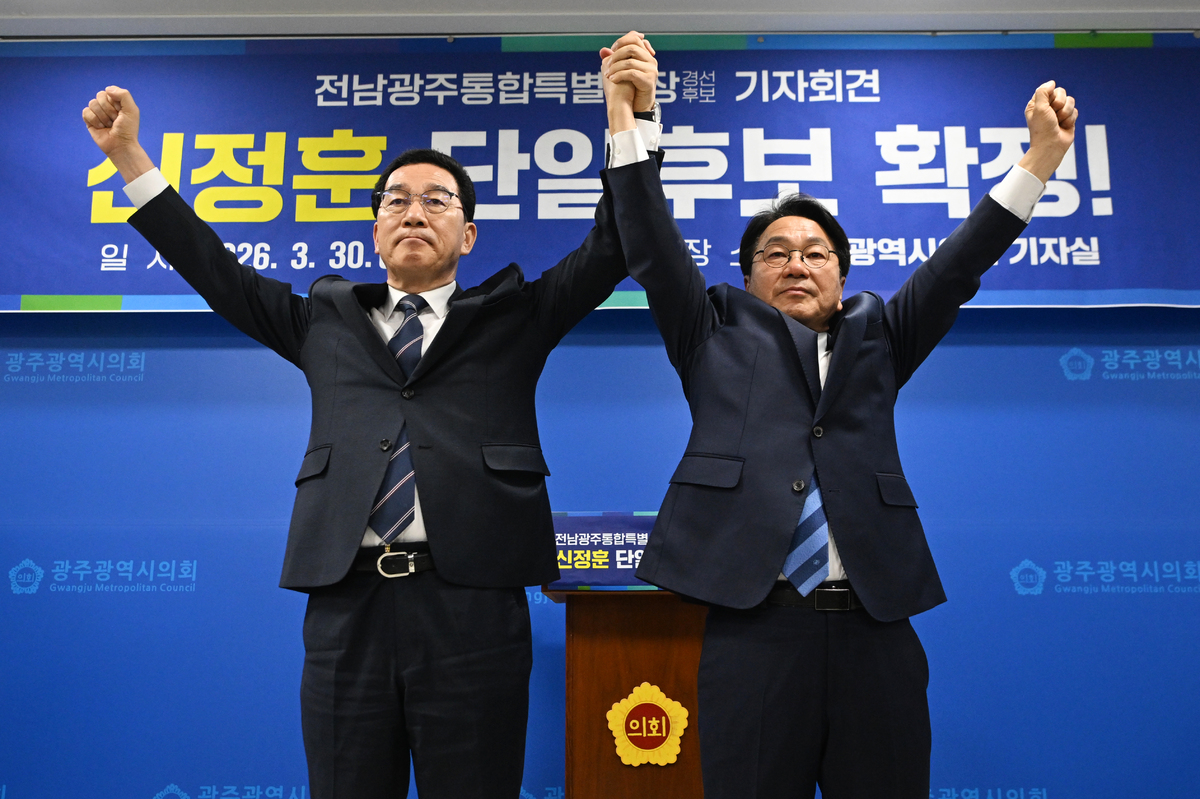 더불어민주당 전남광주통합특별시장 본경선 주자인 신정훈(왼쪽)·강기정 예비후보가 30일 오전 광주 서구 광주시의회에서 양측간 후보 단일화 확정 입장을 밝히고 서로 악수하고 있다. 뉴시스