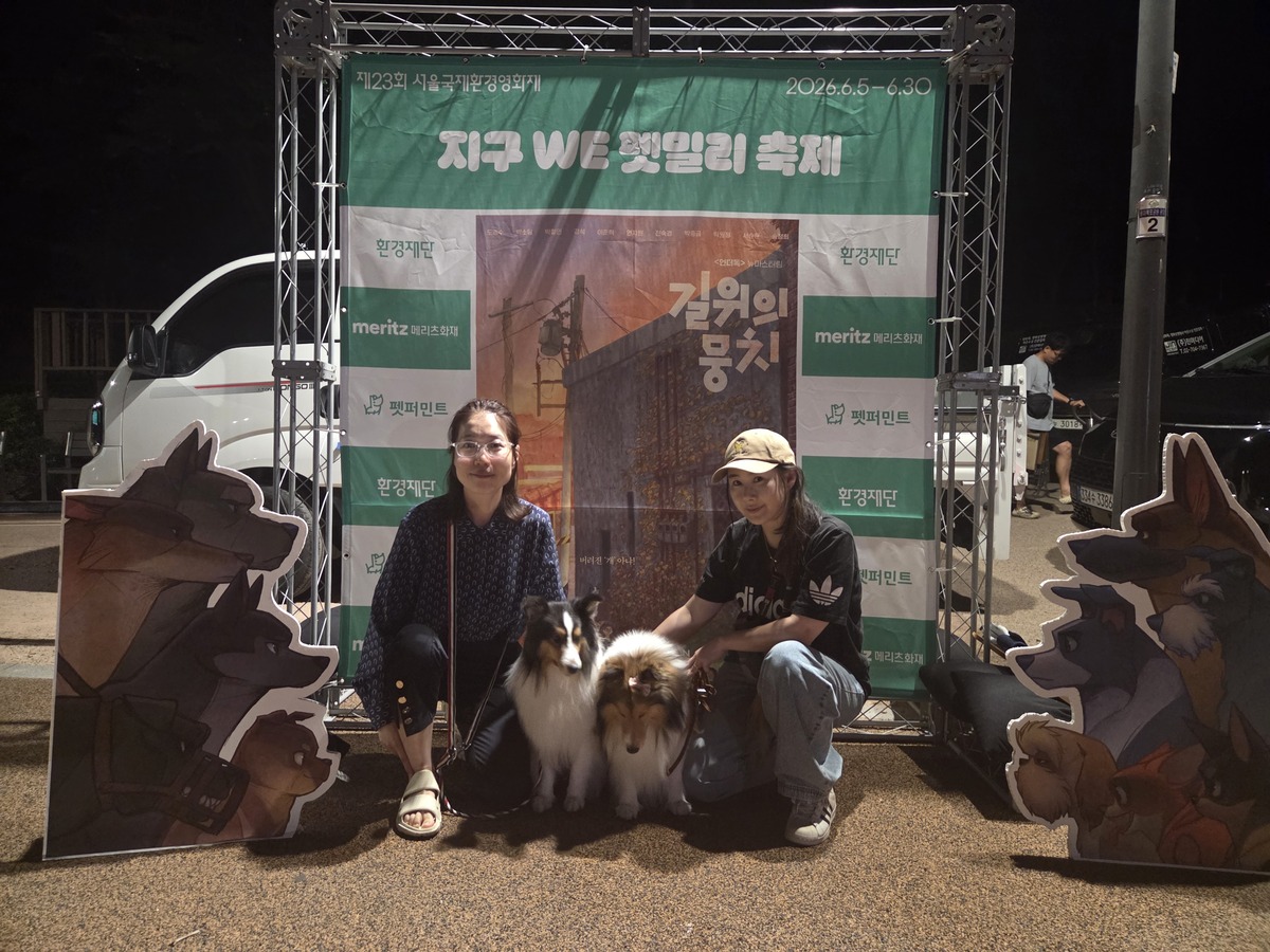 셔틀랜드십독 굿보이&amp;전설이와 보호자들이 야외 상영회 포토존에서 기념사진을 찍고 있다. 박재림 기자