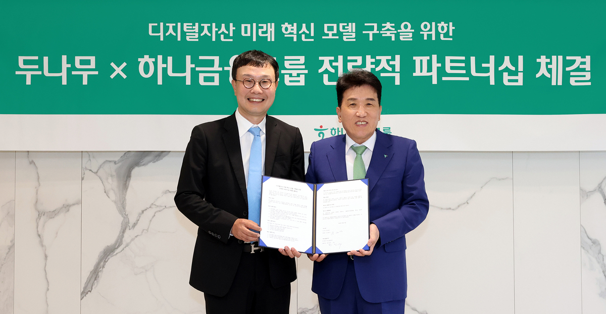 하나금융그룹은 지난 5월 하나은행을 통해 국내 최대 가상자산 인프라를 보유한 ‘두나무’에 대한 1조원 규모 지분을 취득하고,&nbsp;금융과 디지털자산을 연계한 미래혁신모델 구축을 위한&nbsp;전략적 업무협약을 체결했다. 이날 하나금융그룹 명동사옥에서 개최된 협약식에 참석한 함영주 하나금융그룹 회장(오른쪽)과&nbsp;김형년 두나무 부회장이&nbsp;함께 협약서를 들고 기념촬영을 하고 있다. 하나금융그룹 제공