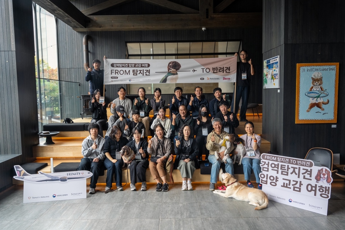 은퇴 검역탐지견과 입양가족, 예비 입양가족의 1박2일 교감여행 참가자들과 주최 측인 트리니티항공·소노인터내셔널·농림축산검역본부 관계자들, 은퇴 검역탐지견들이 기념사진을 찍고 있다. 소노인터내셔널 제공